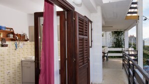 A balcony with a view of the sea, a wooden door, and a small kitchen area with a sink and cabinets. - A2 Large apt With the big Terrace & Great sea View (Trogir)