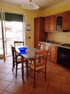 Una cocina con armarios de madera, una estufa a gas y una mesa de comedor con sillas.