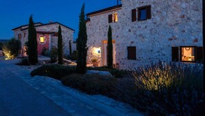 Un edificio in pietra con vialetto lastricato e piante in vaso.