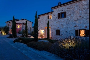 A stone building with a paved driveway and potted plants.