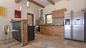 Una cucina moderna con mobili in legno, un frigorifero in acciaio inossidabile e un pavimento in pietra.