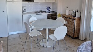Une cuisine moderne avec des meubles blancs, une table de salle à manger ronde et quatre chaises blanches.