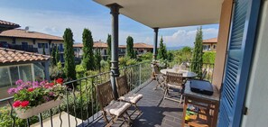 A balcony with a table and chairs, a flower planter, and a grill.