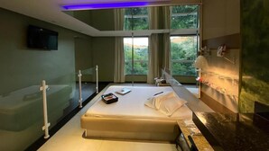 A modern hotel room with a bed, a flat-screen TV, a large window with curtains, and a bathroom with a mirror and towel rack. - Cequisabe Motel (Juiz de Fora)