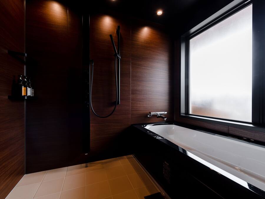 Un baño moderno con una bañera grande, ducha y ventana que proporciona luz natural.