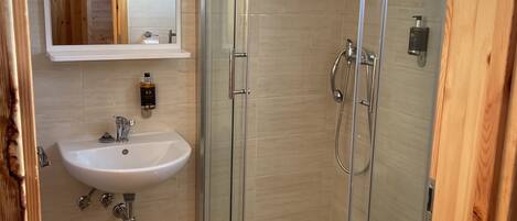 Ein modernes Badezimmer mit einer gläsernen Duschkabine, einem weißen Waschbecken und einer Toilette.
