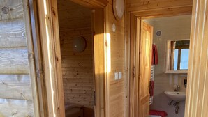 A wooden interior with a visible bathroom, a bed, and a door leading to another room. - Chata pri Jazere 1 - Lake Side Cottage (Horná Potôn)