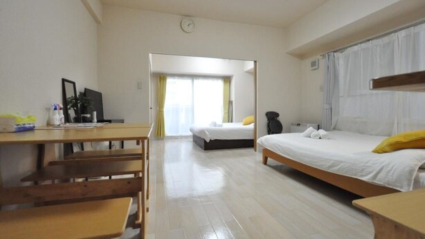 Una habitación de hotel con un escritorio de madera, dos camas, un espejo y un reloj en la pared.