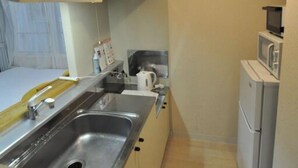 Una cocina compacta con pileta, microondas y refrigerador.