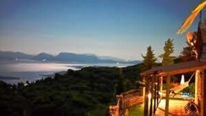 Vista costera con una estructura de madera que domina una masa de agua y montañas.