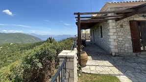 Un edificio de piedra con una pérgola, una maceta grande y vistas a montañas.