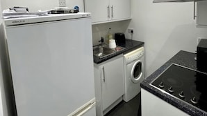 A compact kitchen with a refrigerator, washing machine, and stove. - 1-bed Apartment Next to Paisley Gilmour Station! (Paisley)