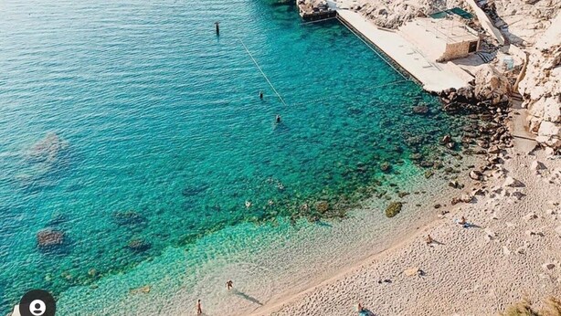 Un litorale con acque cristalline turchesi, un terreno roccioso e una spiaggia sabbiosa.