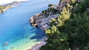 A coastal area with clear blue waters, rocky cliffs, and dense greenery. - Beautiful L&N Studio Apartment in Dubrovnik (Dubrovnik)