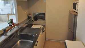 Cocina compacta con lavamanos, armarios, microondas y refrigerador.