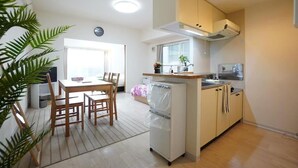 Una cocina compacta con zona de comedor, un refrigerador pequeño y una ventana que proporciona luz natural.