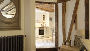 A kitchen with white cabinets, a built-in oven, and a wooden ceiling. - Ecrin Robespierre - Cosy & Romantic apartment with A/C in historical property (Paris)