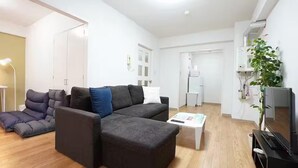 A modern living room with a sectional sofa, a coffee table, and a flat-screen TV. - Shimaya Building 505 (Sapporo)