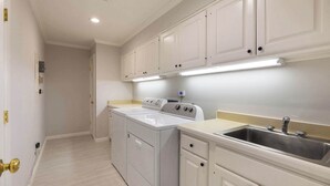 A kitchen with white cabinets, a stainless steel sink, and a built-in washer and dryer. - NEWLY RENOVATED! Expansive 8,800 SF Luxury Home + Walkable to Beaver Creek Village + Hot Tub + Game Rooms (Beaver Creek)