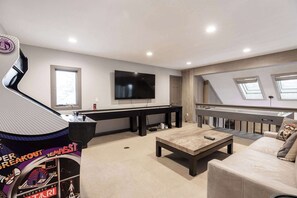 A modern living room with a flat-screen TV, a gaming console, a sofa, and a coffee table. - NEWLY RENOVATED! Expansive 8,800 SF Luxury Home + Walkable to Beaver Creek Village + Hot Tub + Game Rooms (Beaver Creek)
