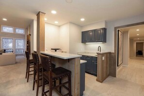 A modern kitchen with a bar area, wooden chairs, and dark cabinets. - NEWLY RENOVATED! Expansive 8,800 SF Luxury Home + Walkable to Beaver Creek Village + Hot Tub + Game Rooms (Beaver Creek)