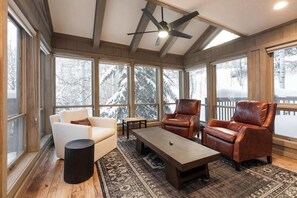 A sunroom with large windows, leather chairs, a coffee table, and a ceiling fan. - NEWLY RENOVATED! Expansive 8,800 SF Luxury Home + Walkable to Beaver Creek Village + Hot Tub + Game Rooms (Beaver Creek)