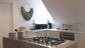 A modern kitchen with a central island, built-in appliances, and a skylight. - Villa Mathë" apartment, view of Roscoff harbour (Roscoff)