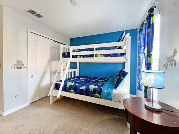 Dormitorio con literas, pared azul, puerta blanca y un escritorio pequeño con lámpara.