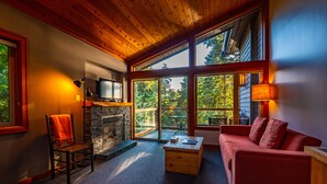 A cozy living room with a fireplace, a red sofa, and a television on a wooden shelf.