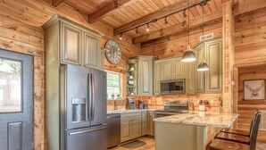 A modern kitchen with wooden cabinets, stainless steel appliances, and a large island. - Massive Views+Indoor Pool+Movie Theater+Fire Pit (Sevierville)