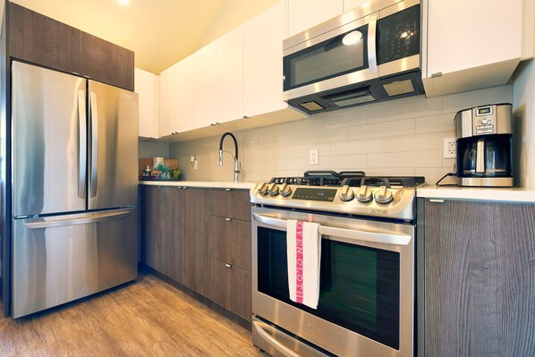 Una cocina moderna con electrodomésticos de acero inoxidable, armarios de madera y salpicadero de azulejos.
