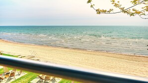 A beach with a view of the ocean, a sandy shore, and some lounge chairs.
