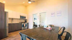 A modern kitchen with wooden cabinets, stainless steel appliances, and a dining area with a wooden table and chairs.