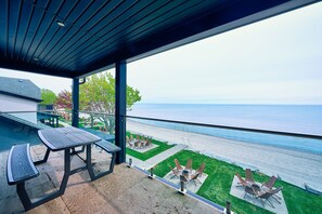 Un patio techado con mesa y sillas, con vista a la playa y al océano.