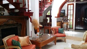 Ein geräumiges Wohnzimmer mit Kamin, bequemen Sitzgelegenheiten und einer Treppe.