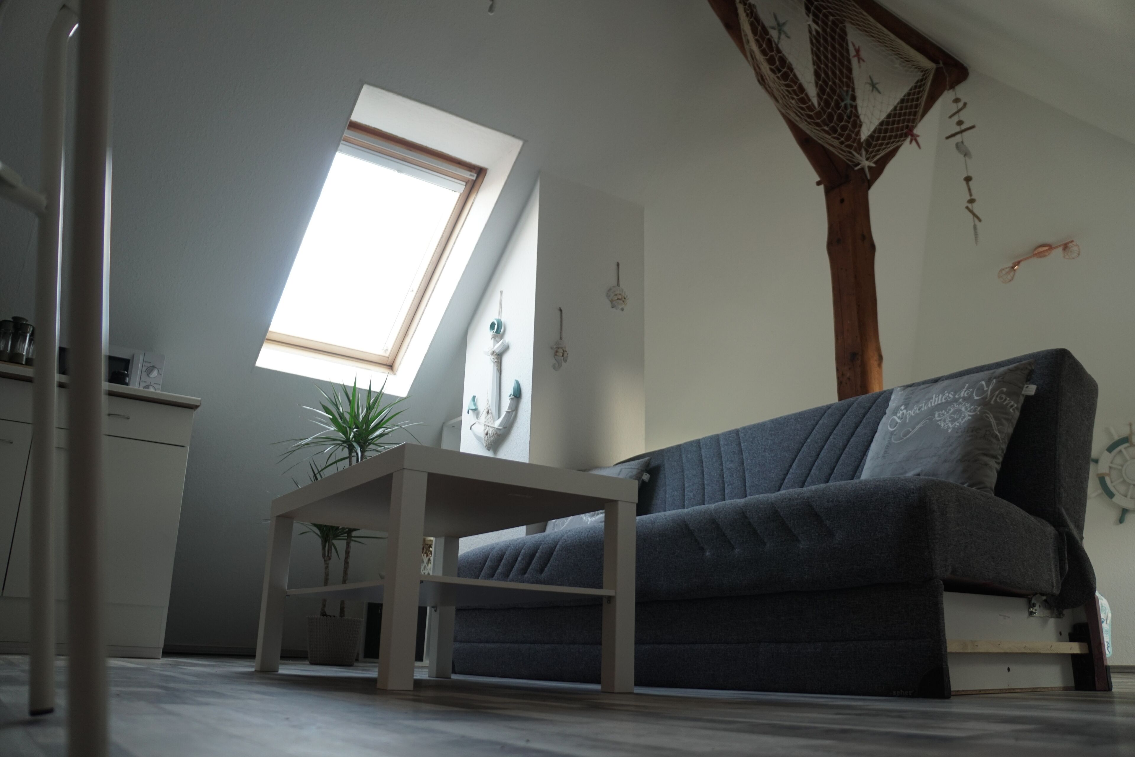 A modern living room with a grey sofa, a small table, and a skylight.