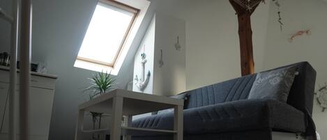 A modern living room with a grey sofa, a small table, and a skylight.