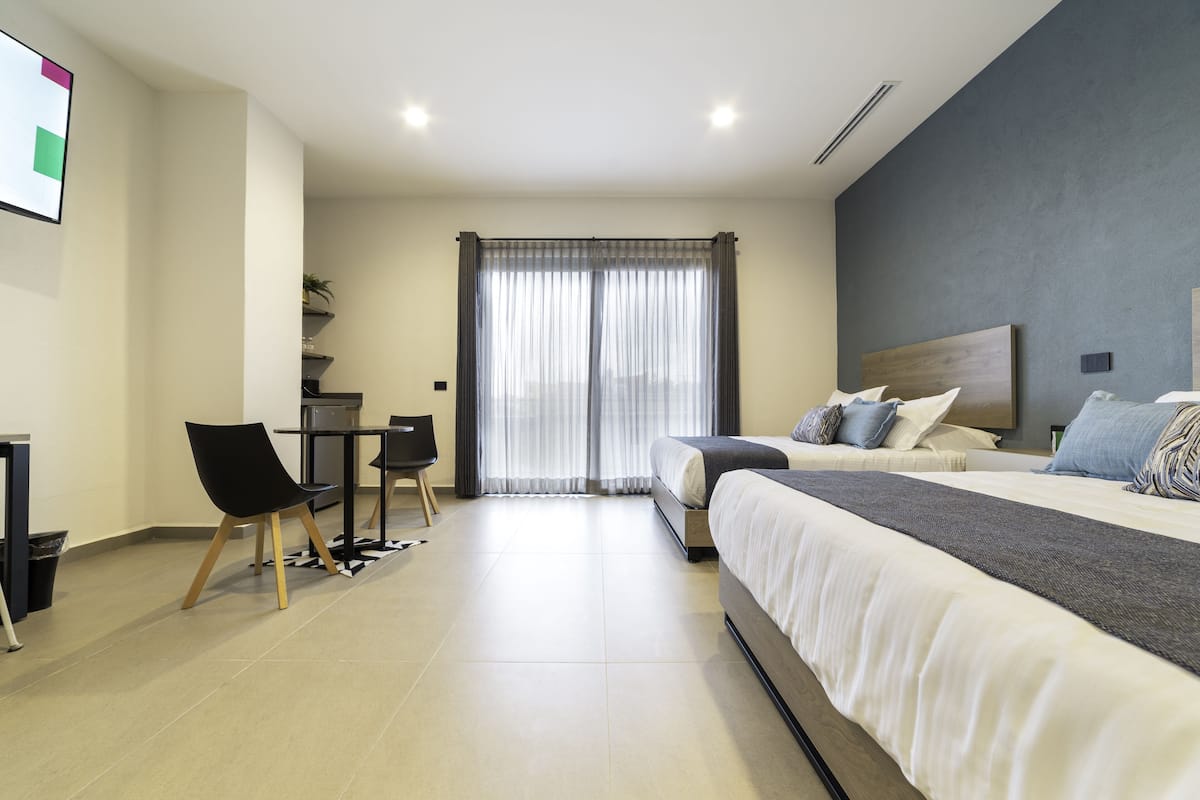 A modern hotel room with a large bed, a desk, and a chair.