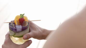Iemand houdt een cocktail met fruitdecoraties vast.