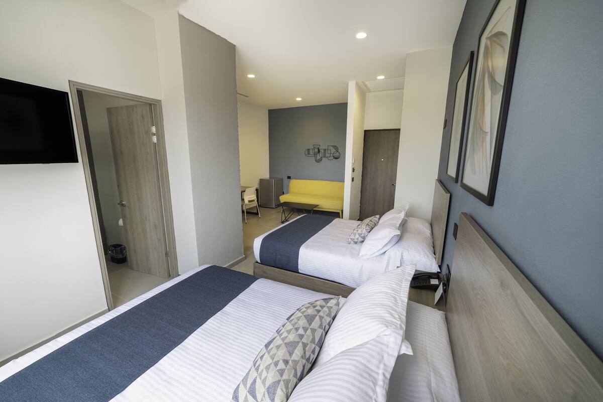 A hotel room with two beds, a TV, a desk, and a chair.