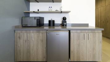 A compact kitchen with a microwave, coffee maker, and a refrigerator.