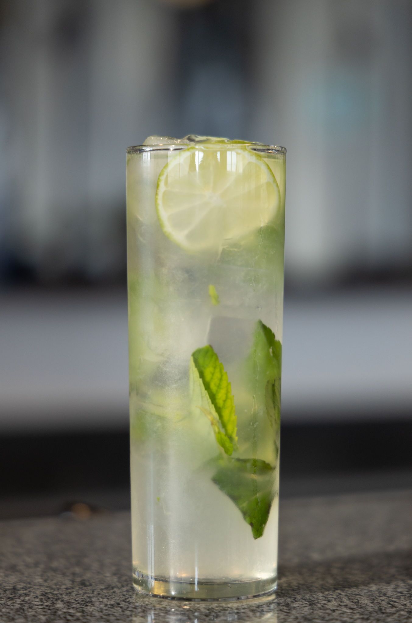 A tall glass with a lime slice and mint leaves, likely containing a beverage.