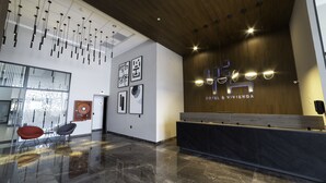 Een moderne receptie met een houten balie, een glazen scheidingswand en een plafond met hangende lampen.