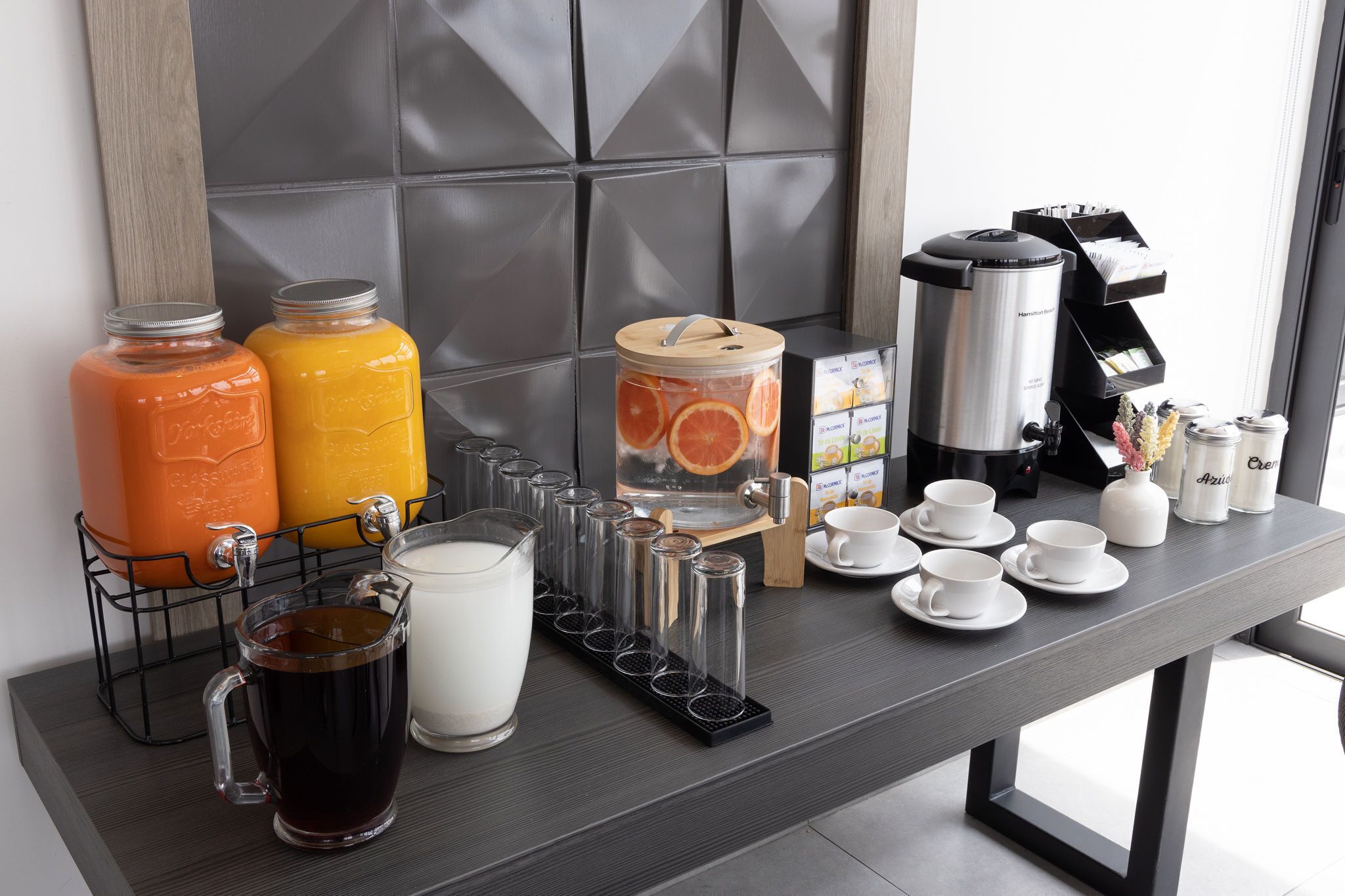 A breakfast bar with orange juice, milk, coffee, and tea.