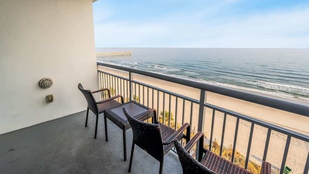 A balcony with wicker furniture overlooking a beach and a pier. - 7th Floor! Modern Building, Direct Oceanfront View (Myrtle Beach)