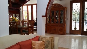 Una sala de estar con un sofá, un mueble de madera y un comedor con sillas y una mesa.