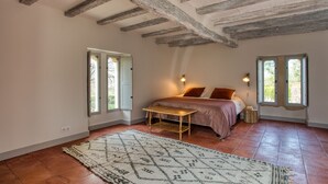 A bedroom with a bed, a wooden table, and a patterned rug.