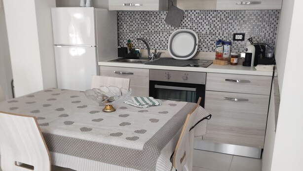 A modern kitchen with a dining table, chairs, and a refrigerator. - Apartment near the sea (Lido di Ostia)