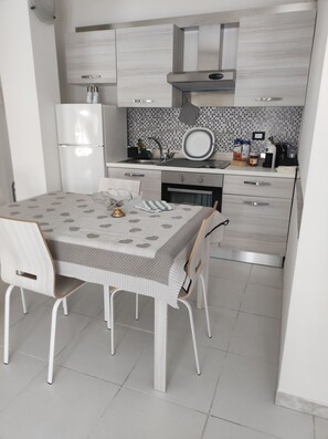 A modern kitchen with a dining table, chairs, and a refrigerator. - Apartment near the ocean (Lido di Ostia)