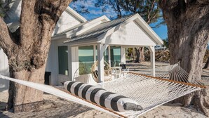 A beach house with a hammock, a covered patio, and a view of the ocean. - The Love Shack: Completely restored 1915 direct beachfront cottage! (BRADENTON BEACH)